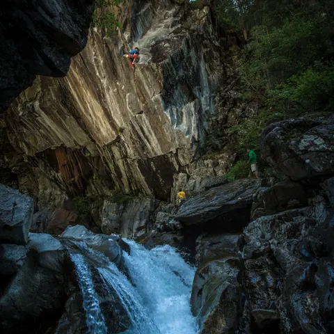 Climbers on a rock wall above a waterfall.
